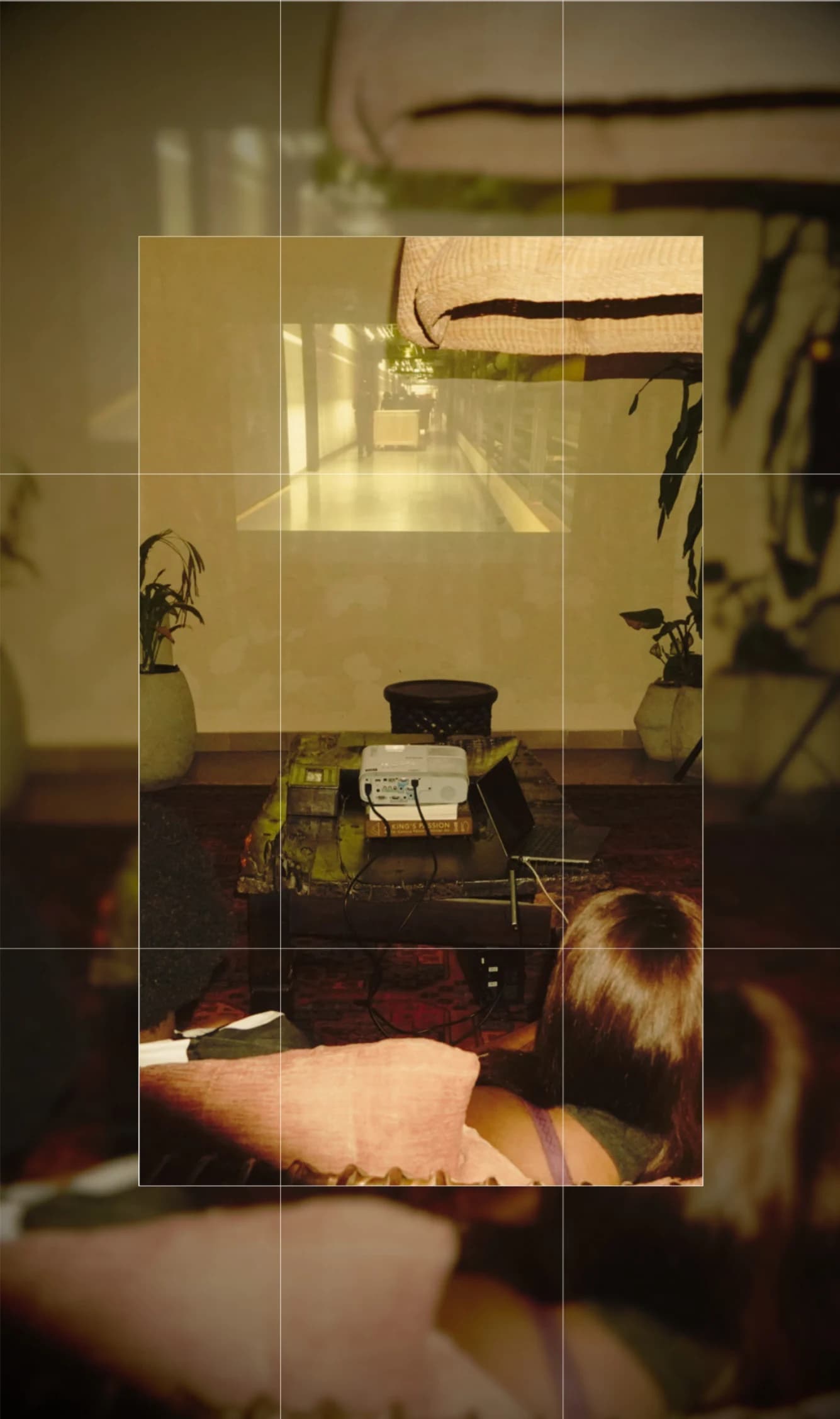 A film projected onto a living-room wall in Lagos while an audience watches from sofas and floor cushions.