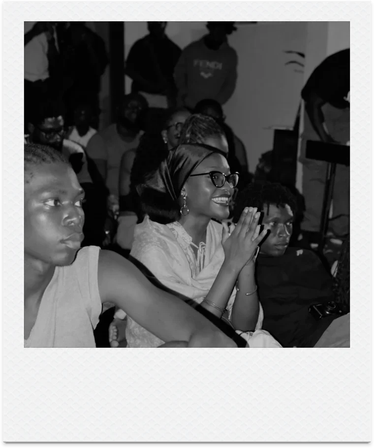Three audience members watching a screening, one smiling with her hands clasped.